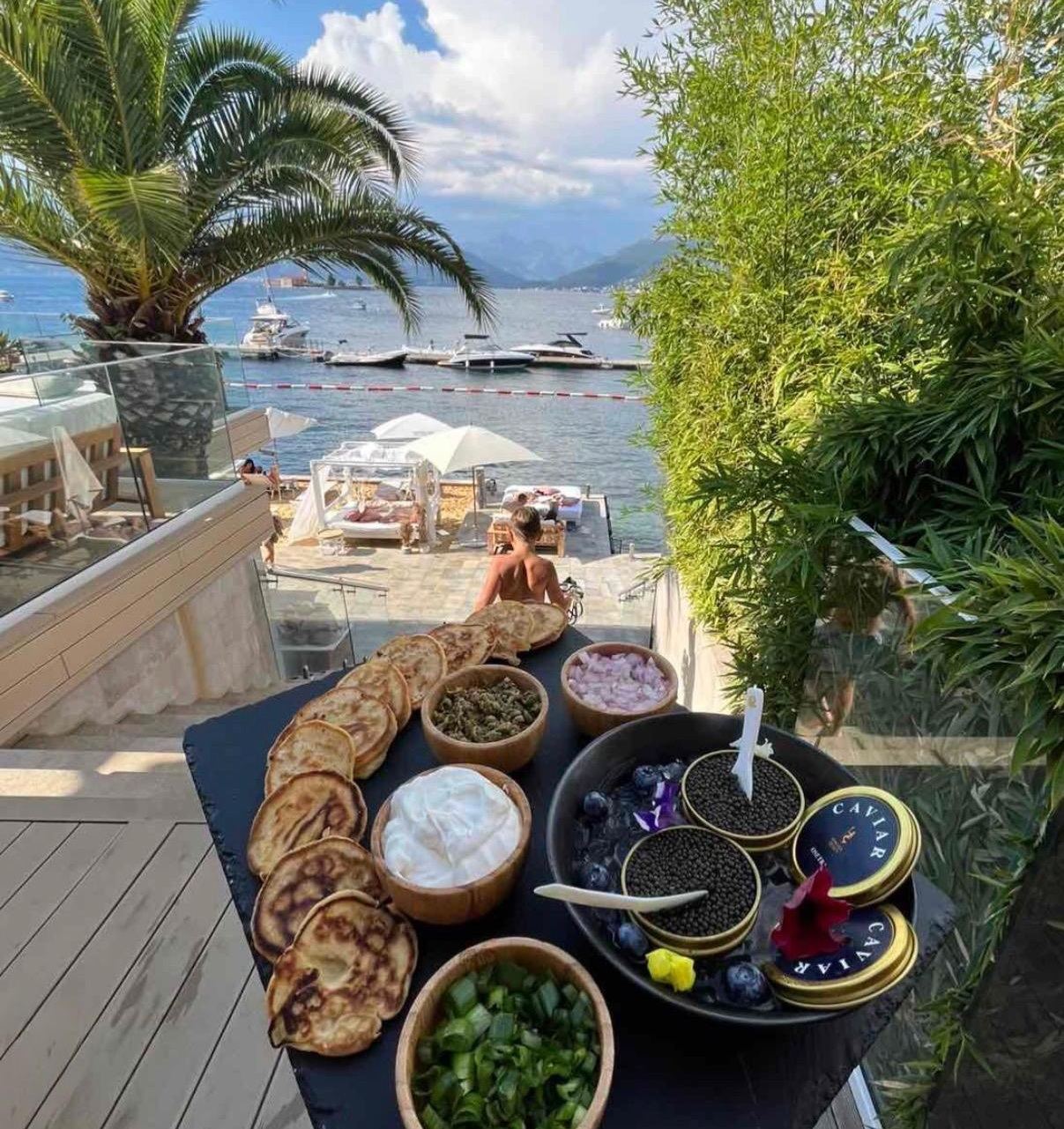Kavijar s palačinkama i prilozima na stolu iznad plaže Monte Palm Beach u Tivtu